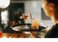 Female server holding a tray of cocktails